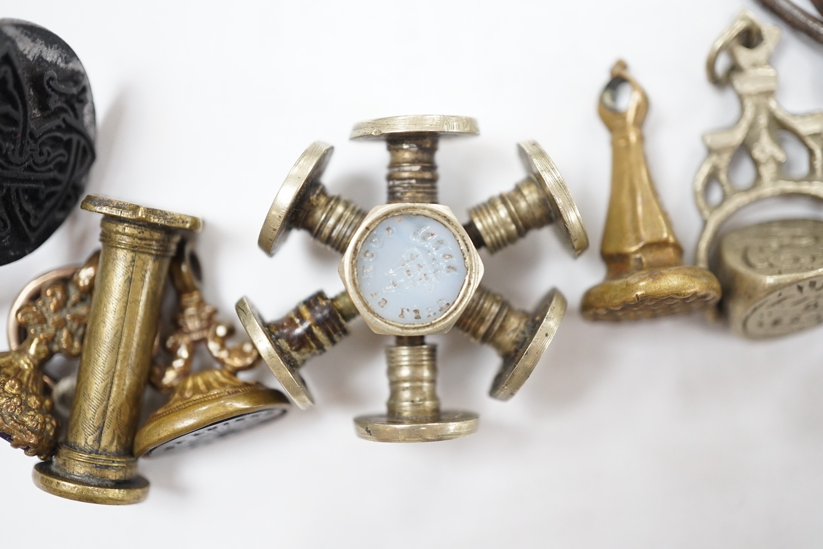 A group of twenty-five steel, gilt metal or nickel fob or desk seals, mostly 19th-century, including a steel swivel seal, a seal with boxwood finial modelled as a hand holding a ball and a nickel multi seal